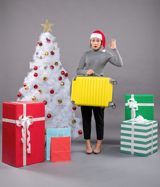 Femme Portant Un Chapeau De Père Noël Avec Des Bagages à Côté De L'arbre De Noël