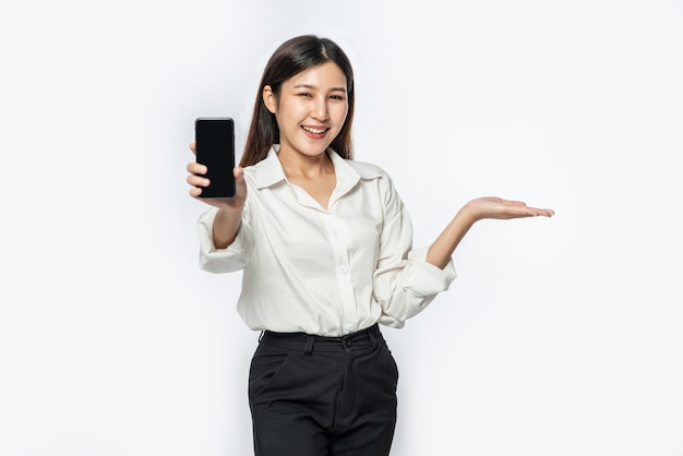 Une femme portant une chemise et tenant un smartphone