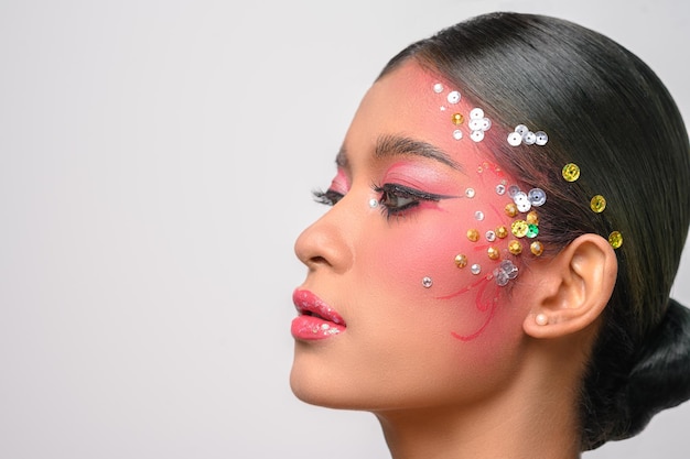 Femme portant du maquillage rose et des embellissements sur son visage isolé sur blanc