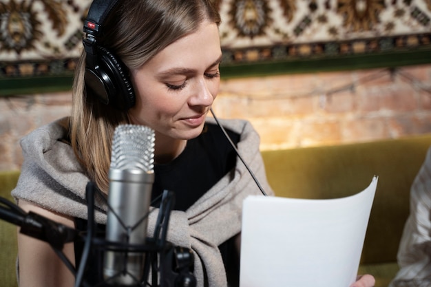 Photo gratuite femme portant des écouteurs exécutant un podcast et utilisant un microphone