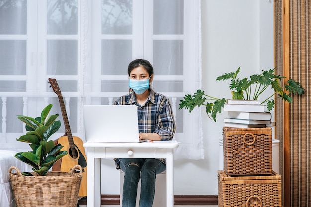 Une femme portant un masque Hygiène est assise au bureau avec un ordinateur portable.