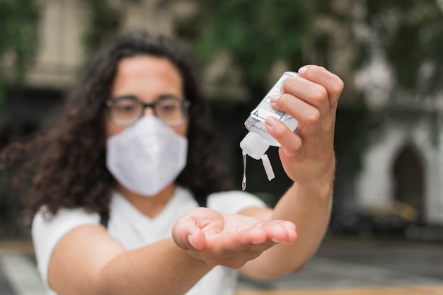 Femme portant un masque médical à l'aide d'un désinfectant pour les mains