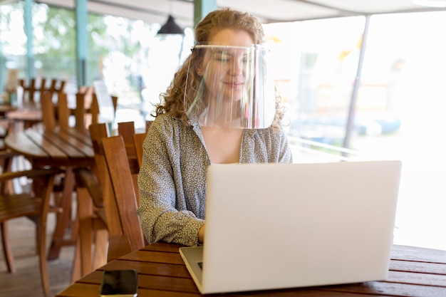 Femme Portant Une Protection Du Visage Tout En Travaillant Sur Un Ordinateur Portable