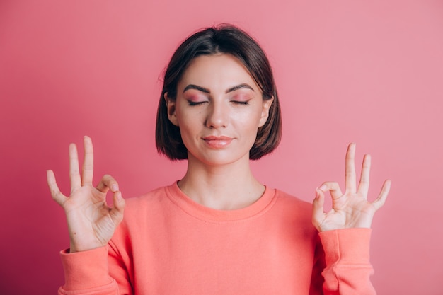 Femme portant un pull décontracté sur fond se détendre et souriant avec les yeux fermés faisant le geste de méditation avec les doigts. Concept de yoga.