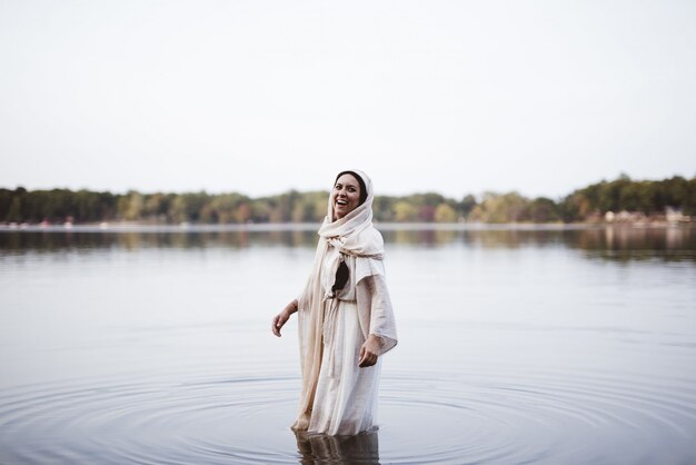 Femme portant une robe biblique et riant debout dans l'eau