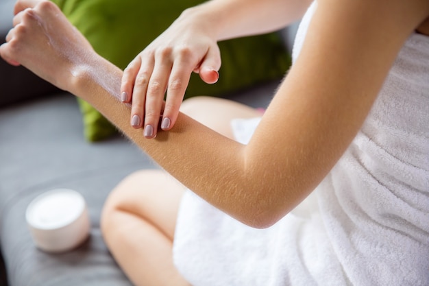 Femme portant une serviette faisant sa routine quotidienne de soins de la peau à la maison.