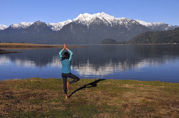 Femme portant des vêtements de sport, tenant une pose de yoga devant le lac calme et les montagnes