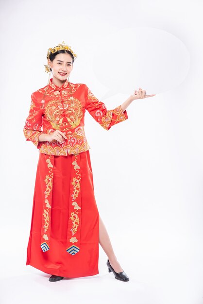 Une femme porte un costume Cheongsam et une chaussure noire heureuse d'obtenir de nouvelles choses pour surprendre le nouvel an chinois