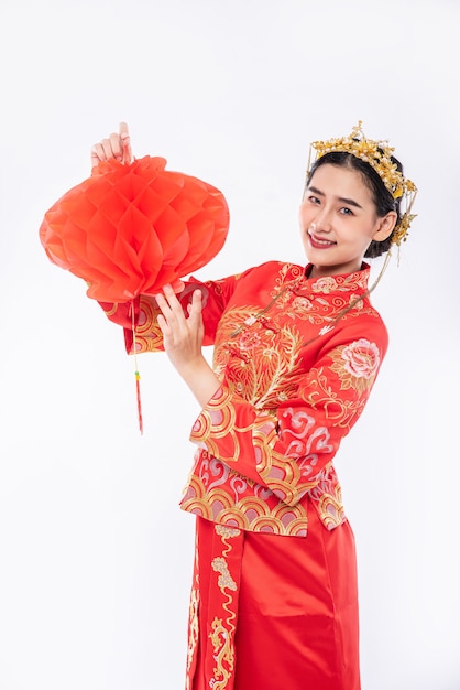 Une femme porte un costume Cheongsam pour promouvoir la lampe rouge au client lors du nouvel an chinois