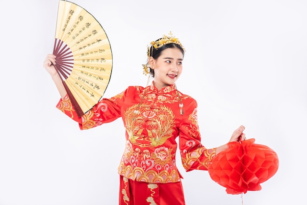 Photo gratuite femme porter un costume cheongsam tenir l'éventail chinois et la lampe rouge pour montrer le grand événement du nouvel an chinois