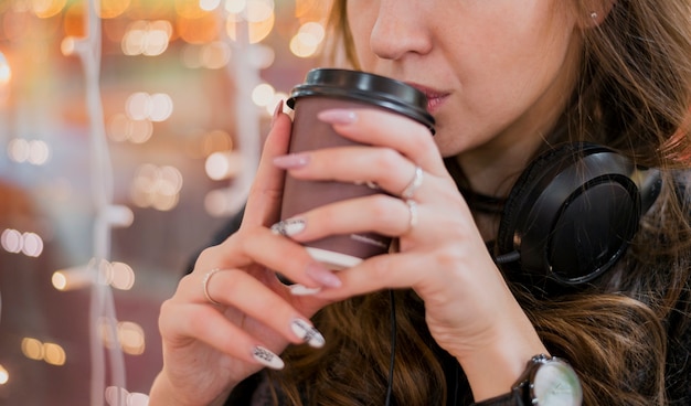 Femme, Porter, écouteurs, boire, tasse, noël, lumières