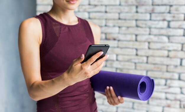 Femme, porter, yoga, natte, regarder, téléphone