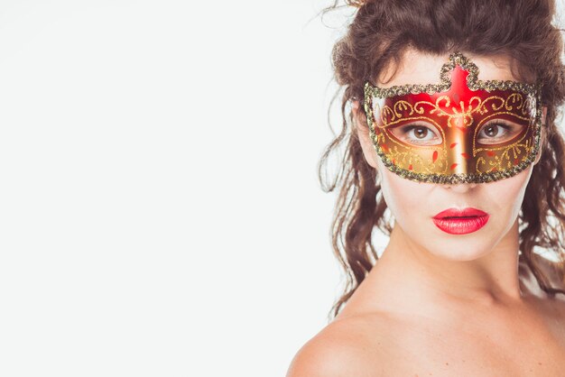 Femme posant dans un masque rouge et or