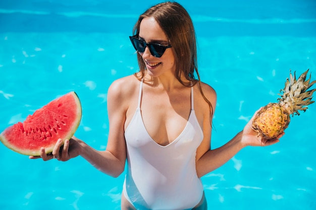 Femme posant dans la piscine avec ananas et melon d&#39;eau