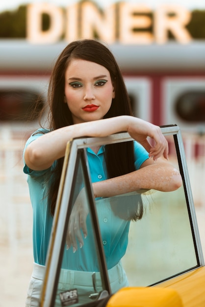 Photo gratuite femme posant dans un style rétro à côté de la voiture
