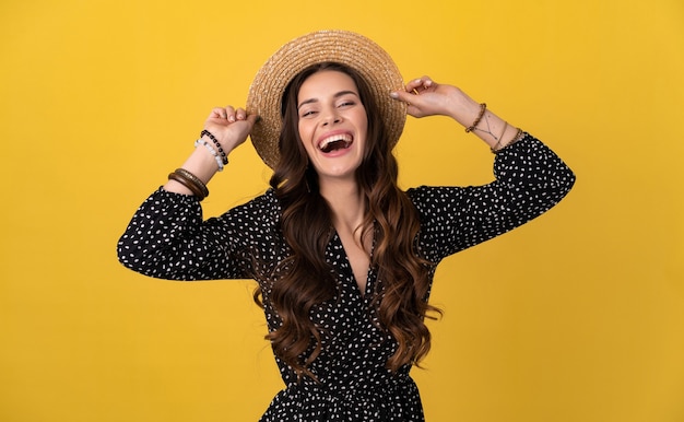 Photo gratuite femme posant isolée sur jaune portant une robe noire à pois et un chapeau de paille boho élégant