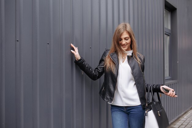 Femme posant une main sur un sac de mur et le shopping sur l&#39;autre