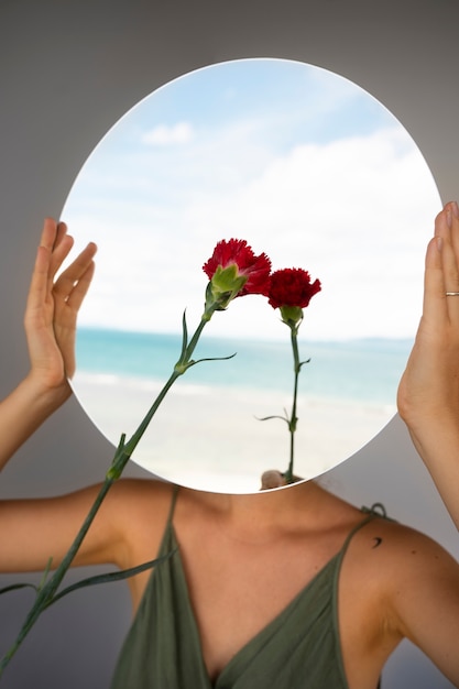 Photo gratuite femme posant avec miroir rond et fleur