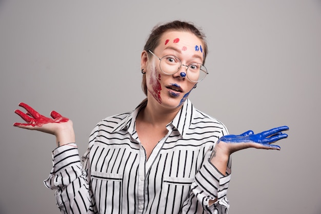 Femme posant avec des peintures sur son visage sur fond gris. Photo de haute qualité