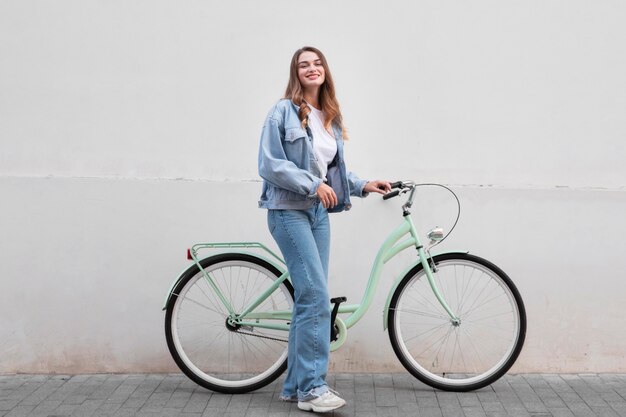 Femme posant tout en tenant son vélo à l'extérieur dans la ville