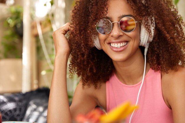 Femme positive ravie dans des lunettes de soleil rondes à la mode