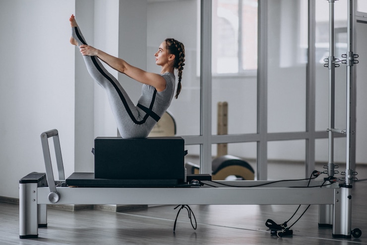 Photo gratuit femme pratiquant le pilates dans un reformeur de pilates