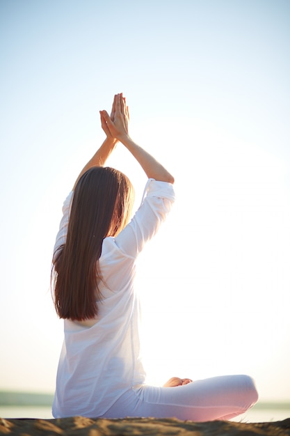 Femme pratiquant le yoga au bord de la mer