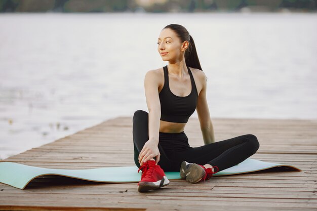 Femme pratiquant le yoga avancé au bord de l'eau