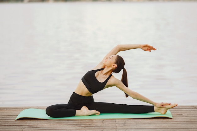 Femme pratiquant le yoga avancé au bord de l'eau