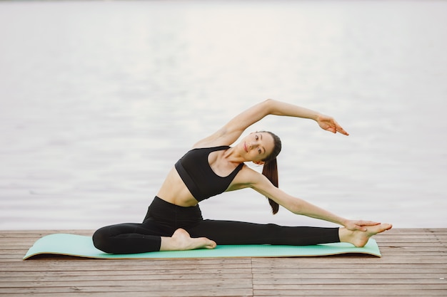 Femme pratiquant le yoga avancé au bord de l'eau