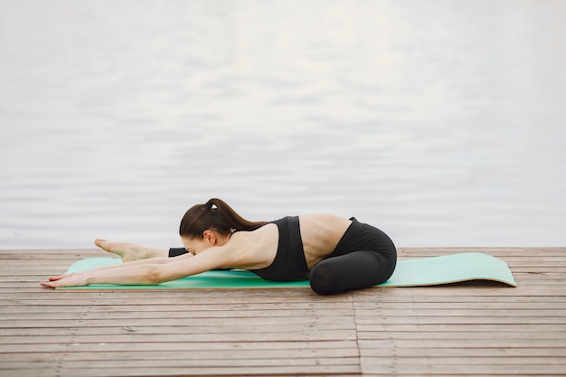 Femme pratiquant le yoga avancé au bord de l'eau