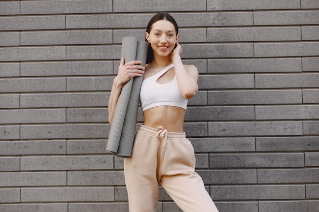 Femme pratiquant le yoga avancé contre un mur urbain sombre