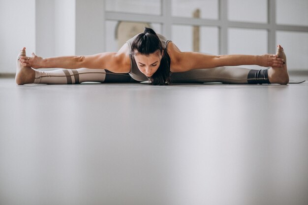 Femme pratiquant le yoga dans la salle de sport sur un tapis