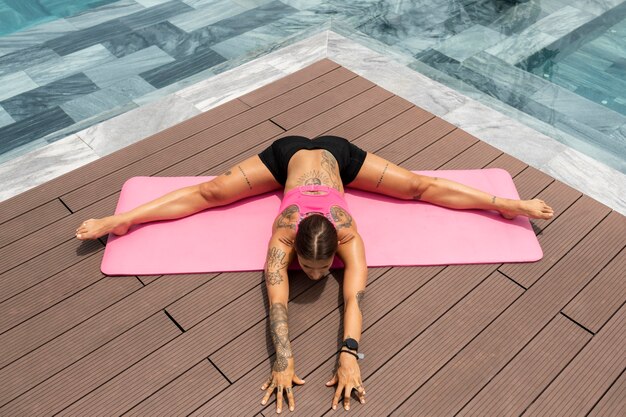 Femme pratiquant le yoga en plein air au bord de la piscine