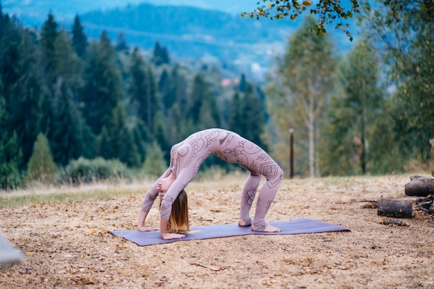 Une femme pratique le yoga le matin dans un parc au grand air.