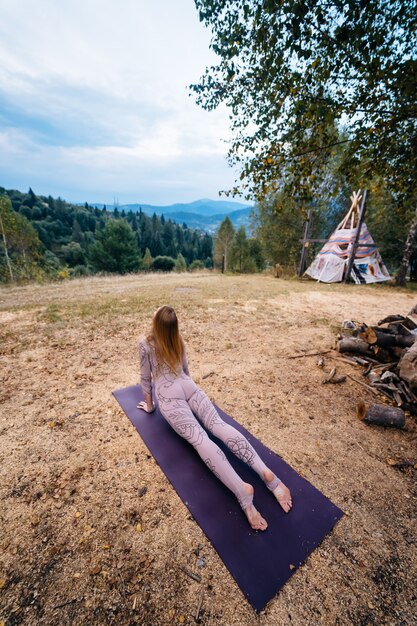 Une femme pratique le yoga le matin dans un parc au grand air.