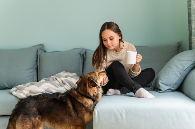 Femme prenant un café à la maison avec son chien pendant la pandémie