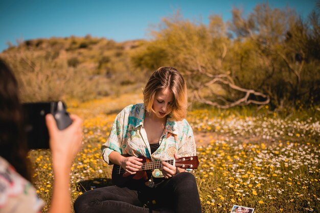 Femme prenant la photo d&#39;un ami avec ukulélé