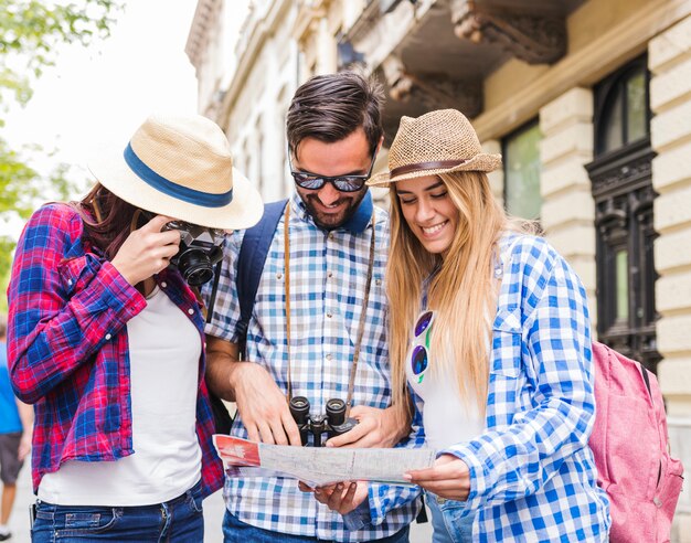 Femme prenant une photo sur l&#39;appareil photo tandis que ses amis en regardant la carte