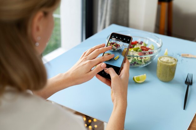 Femme prenant une photo d'un bol avec salade et moitié d'avocat