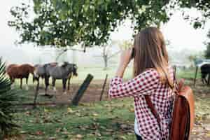 Photo gratuite femme prenant une photo de chevaux