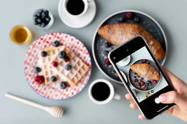 Femme prenant une photo de croissant aux fruits