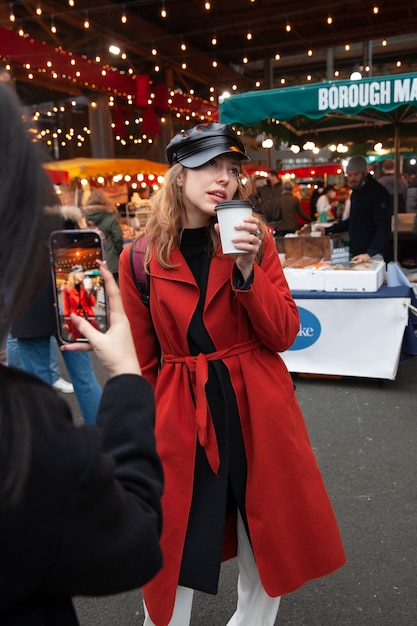 Femme prenant une photo d'une influenceuse au marché