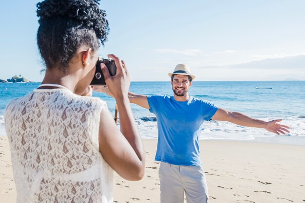 Femme prenant photo de petit ami à la plage