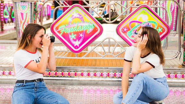 Femme prenant une photo de son amie assise au parc d&#39;attractions