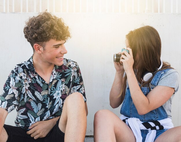 Femme prenant la photo de son petit ami souriant avec une caméra