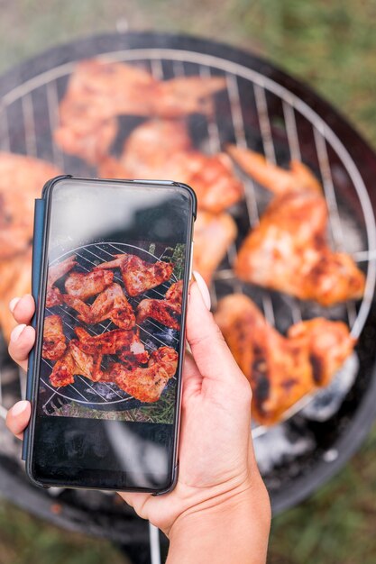 Femme prenant une photo de la viande sur le gril