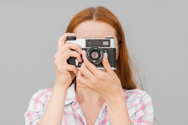 Femme prenant la photo sur la vieille caméra en studio