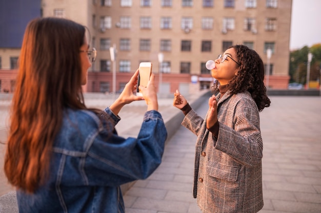 Photo gratuite femme prenant des photos de son ami faisant des bulles à l'extérieur