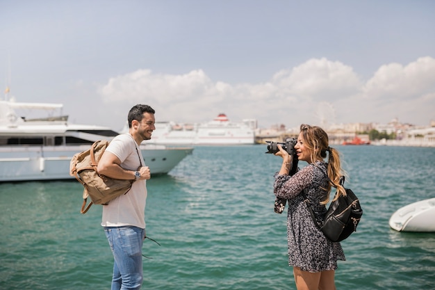 Femme prenant un pica de son petit ami devant une caméra près de la mer